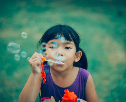 Young girl with bubbles at summer camp is happy she does not have lice because her parents were prepared